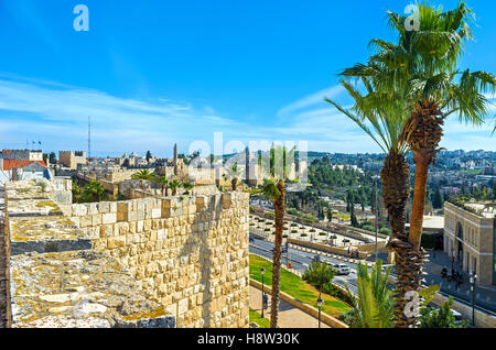 The old city walls surrounded by scenic palms and lush gardens, making the ramparts walk more joyful, Jerusalem, Israel. Stock Photo