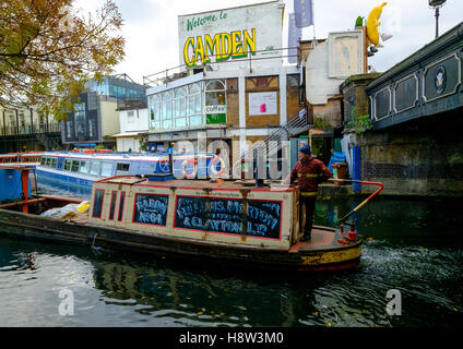 A narrowboat carrying cargo manoeuvring through Camden Town at Camden Lock on the Regents Canal, a world away from the nearby fa Stock Photo