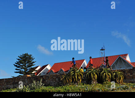 South Africa: children walking in single file on a stone wall in Port Elizabeth, The Friendly City or The Windy City, with red roofs on the background Stock Photo