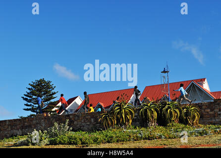 South Africa: children walking in single file on a stone wall in Port Elizabeth, The Friendly City or The Windy City, with red roofs on the background Stock Photo
