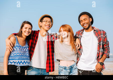 Multiethnic group of cheerful young people standing and laughing together Stock Photo