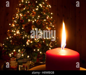 Bright candle burning in front of a Christmas tree Stock Photo