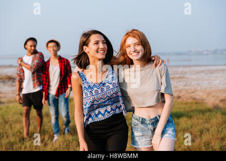 Two cheerful young men and women walking and laughing outdoors Stock Photo