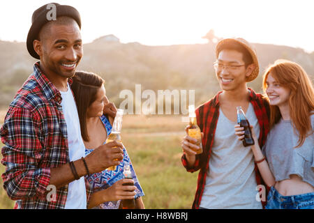 Two cheerful multiethnic couples drinking beer and soda outdoors Stock Photo