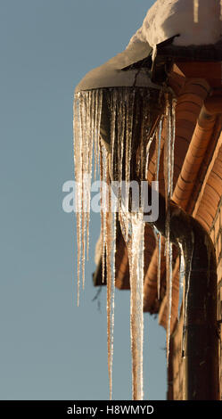Ice needles with Water Spout with brick walled building. Stock Photo