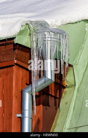 Ice needles with Water Spout with brick walled building. Stock Photo
