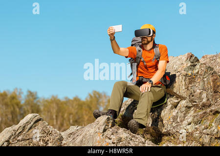 Bearded young man makes selfie in glasses virtual reality outdoors Stock Photo