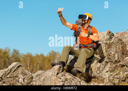 Bearded young man makes selfie in glasses virtual reality outdoors Stock Photo