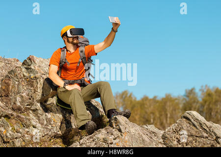 Bearded young man makes selfie in glasses virtual reality outdoors Stock Photo