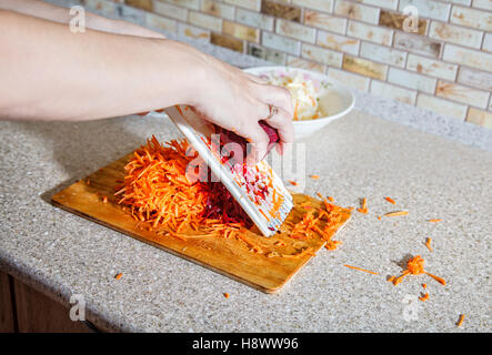 woman cooks the beets with carrot on a grater hands closeup Stock Photo