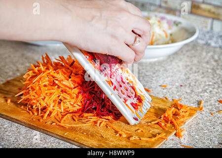woman cooks the beets with carrot on a grater hands closeup Stock Photo