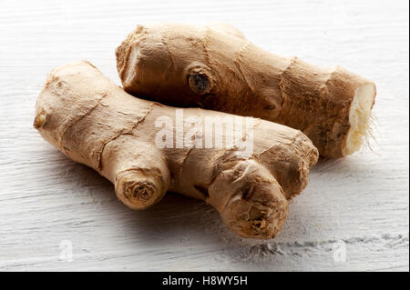 Fresh raw root ginger on a textured white board for use in cooking as a healthy pungent aromatic seasoning Stock Photo
