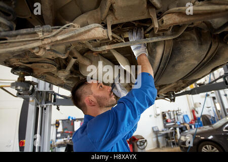 mechanic man with flashlight repairing car at shop Stock Photo