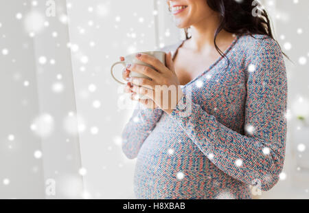 close up of pregnant woman with tea cup at window Stock Photo