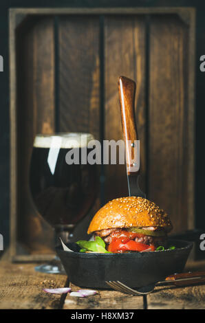 Beef burger with crispy bacon in pan and dark beer Stock Photo