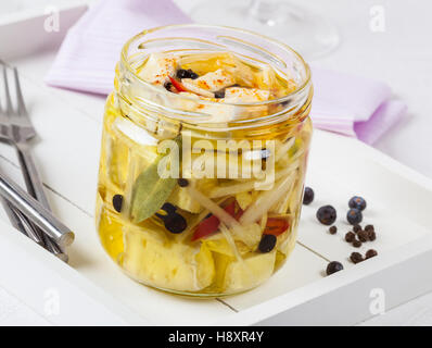 Cheese with herbs and spices in olive oil in a glass jar. Stock Photo