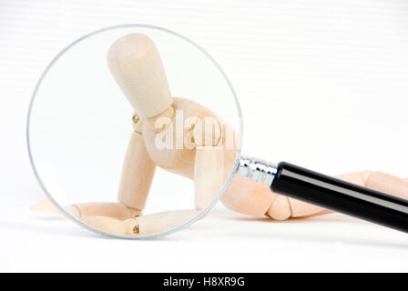 Jointed doll under magnifying glass, symbolic of transparent human Stock Photo