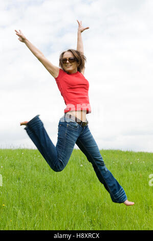 Young, agile woman, 30, jumping on a lawn Stock Photo