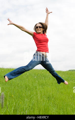 Young, agile woman, 30, jumping on a lawn Stock Photo