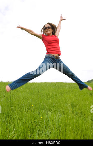 Young, agile woman, 30, jumping on a lawn Stock Photo