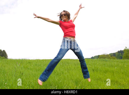 Young, agile woman, 30, jumping on a lawn Stock Photo