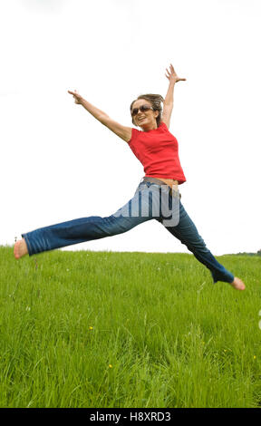 Young, agile woman, 30, jumping on a lawn Stock Photo
