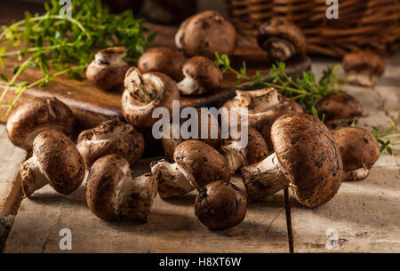 Portobello mushrooms on a wooden table with a cutting board and herbs. Selective focus. Stock Photo