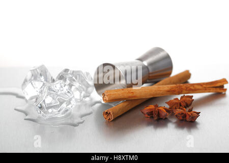 Jigger, melting ice cubes and spices on a stainless steel surface. Stock Photo