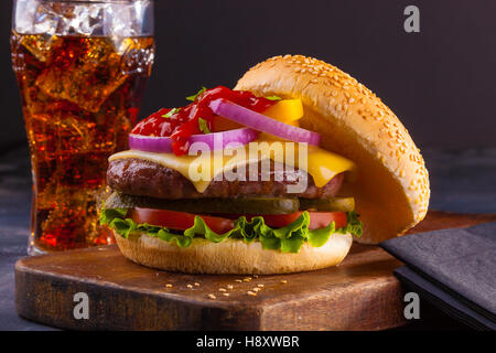 A delicious homemade cheeseburger with red onions, pickles, tomato, lettuce and ketchup. Stock Photo
