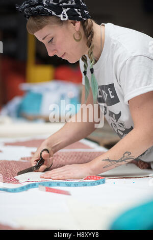 Young tattooed seamstress cutting out a pattern Stock Photo