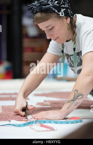 Young tattooed seamstress cutting out a pattern Stock Photo