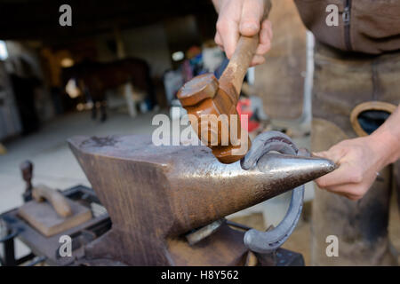 blacksmith forges a horseshoe hammering glowing steel Stock Photo
