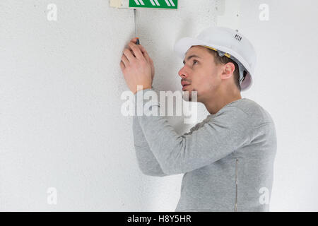 a male electrician fixing electric sign on the ceiling Stock Photo