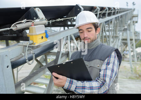 young handsome builder thinking about something and holding a clipboard Stock Photo