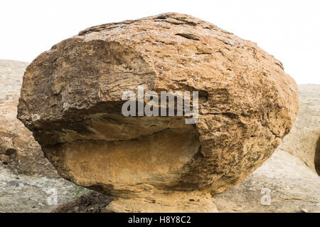 A large spherical sandstone formation with a mouth-like defect and a stone pedestal. Erosion from water gives the stone texture. Stock Photo