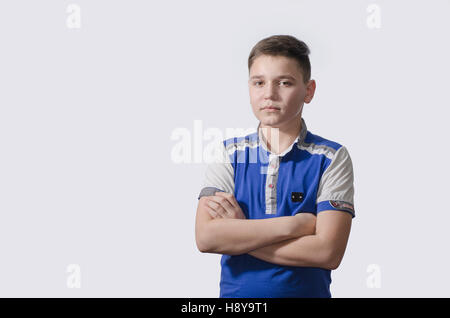 Teenager in blue shirt on a white background with a serious expression on his face. Stock Photo