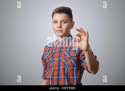 Beautiful teenager in a plaid shirt, showing OK sign on gray-white background Stock Photo