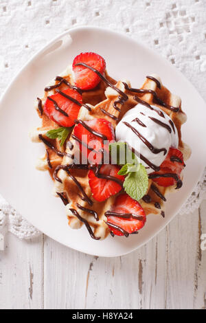 Belgian waffles with strawberries and chocolate topping on a plate. Vertical view from above Stock Photo