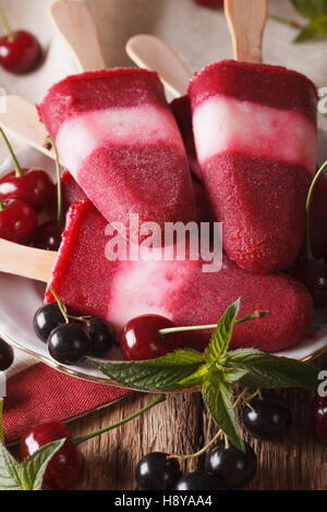 Cherry ice cream with mint close up on a stick on the table. vertical Stock Photo