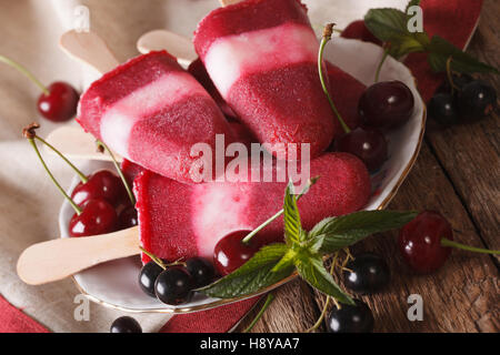 Fruit ice cream with cherry and currants on a stick closeup on a plate. Horizontal Stock Photo