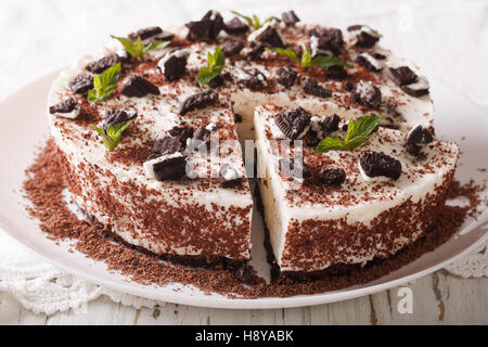 Cheesecake dessert with chunks of chocolate cookies decorated with mint close up on a plate. horizontal Stock Photo