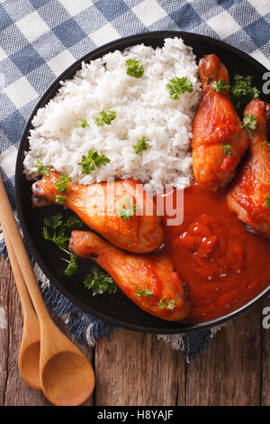 Thai cuisine: chicken leg with spicy chilli sauce Sriracha and Rice close-up on a plate. Vertical view from above Stock Photo