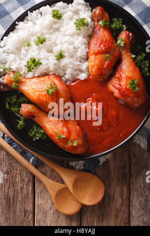 Chicken legs with chilli sauce Sriracha and Rice close-up on the table. Vertical view from above Stock Photo