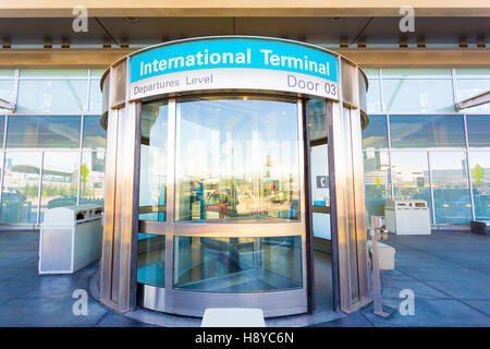Front revolving door provides an entrance to international airport terminal located at departures level. Horizontal Stock Photo