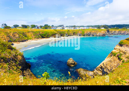 Beautiful azure cove below the cliffs near Main Street on a blue sky day in Mendocino community in California. Horizontal Stock Photo
