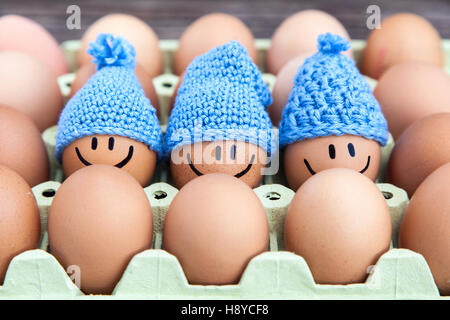 Three eggs wearing blue hats, stay together with happy faces. Stock Photo