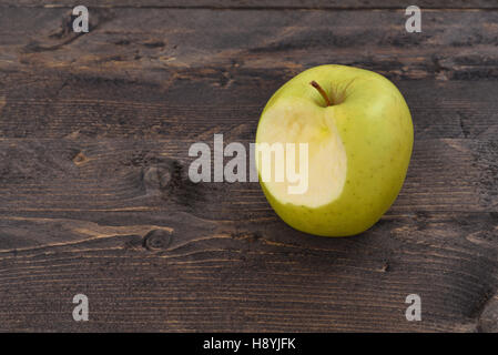 One bitten green apple on a brown wooden desk, top angle view Stock Photo