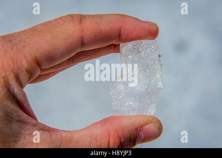 Holding big salt crystal in hand against blue sky Stock Photo