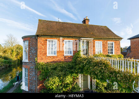 Roadside view of an unusual Georgian style house by the River Dun accessed by a creeper covered bridge in Hungerford, Berkshire, southern England Stock Photo