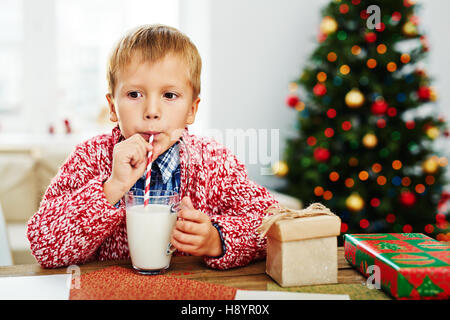 Little boy drinking milk through striped straw Stock Photo